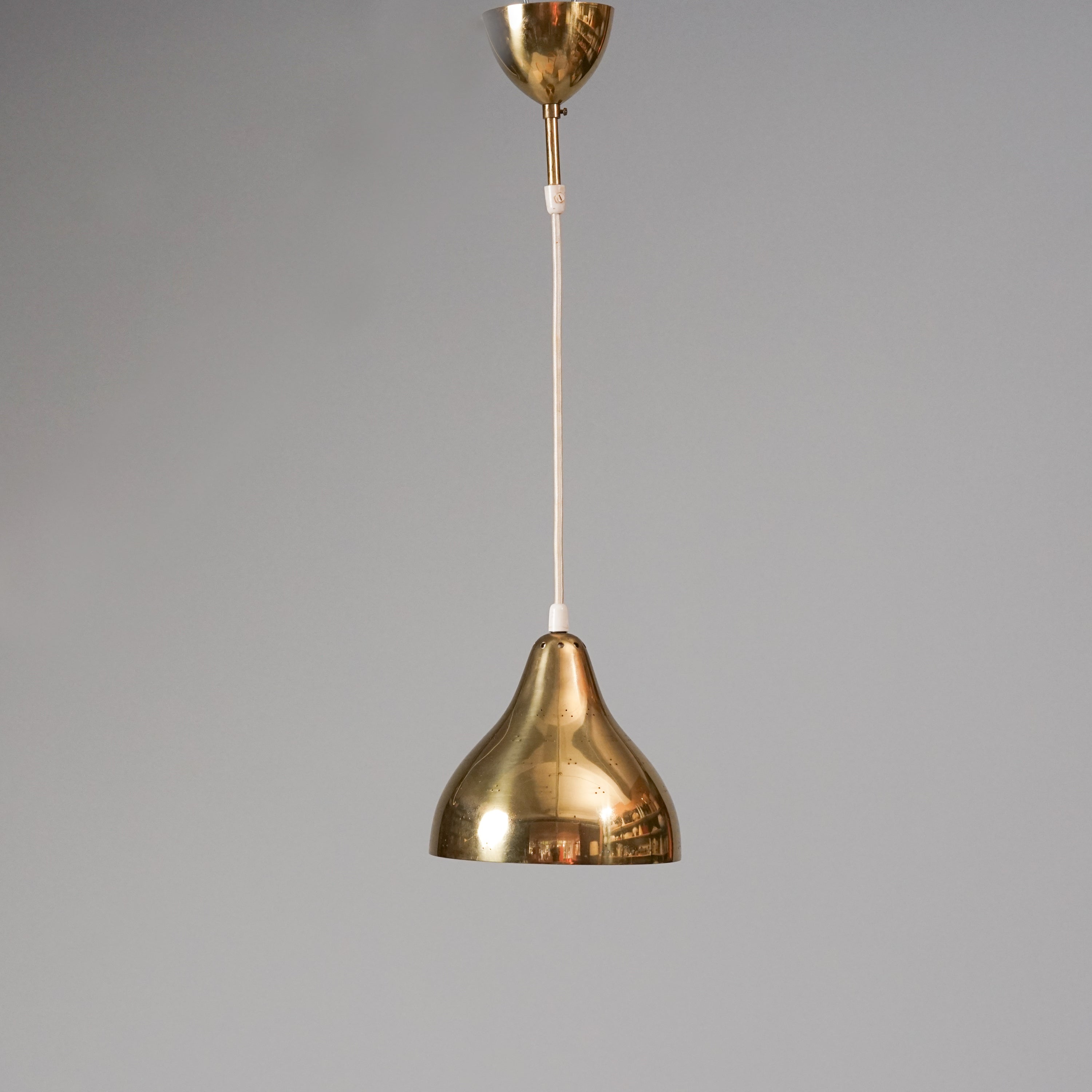 Brass bell-shaped ceiling light. The lamp has small holes that reflect the light. 