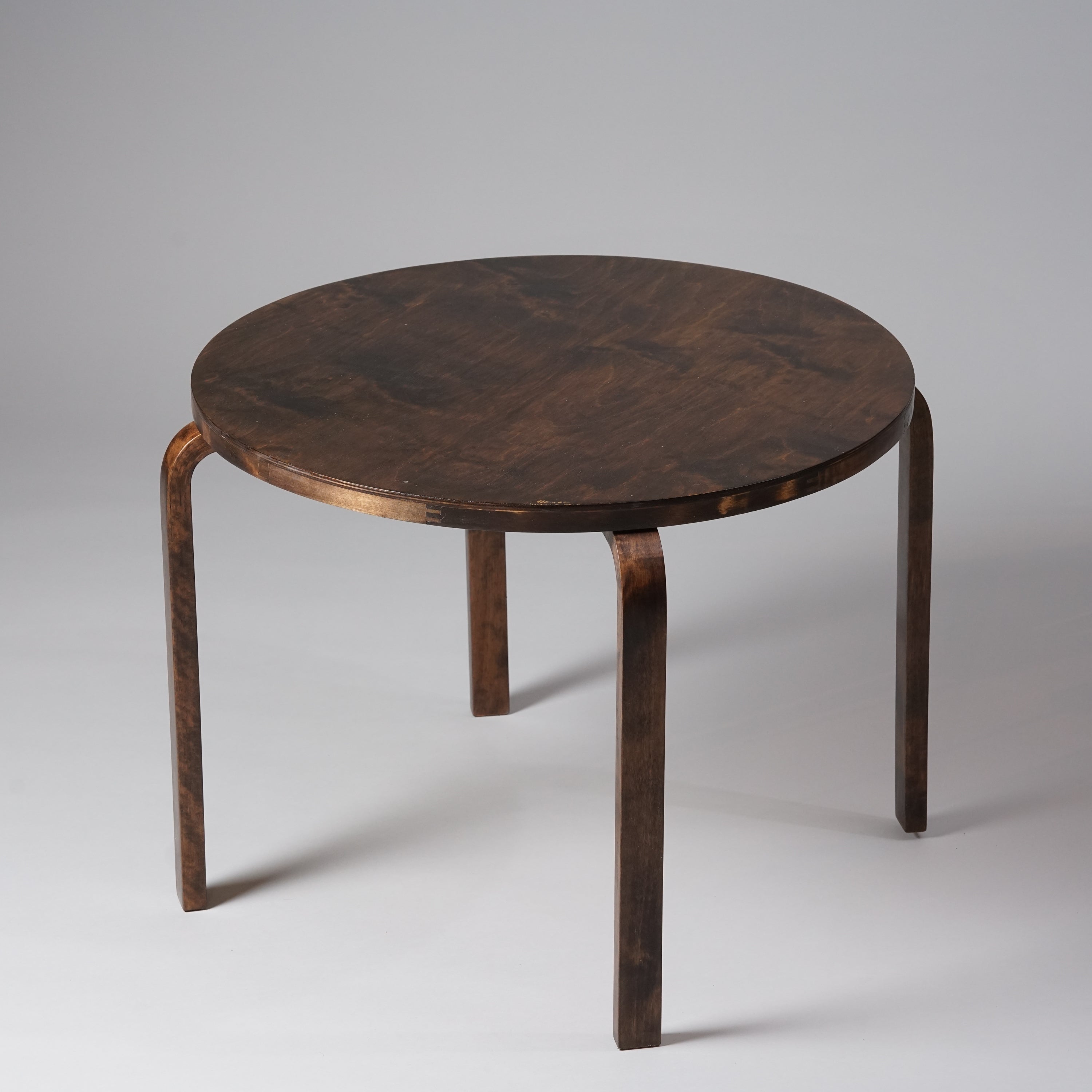 A round wooden table in dark brown color. 
