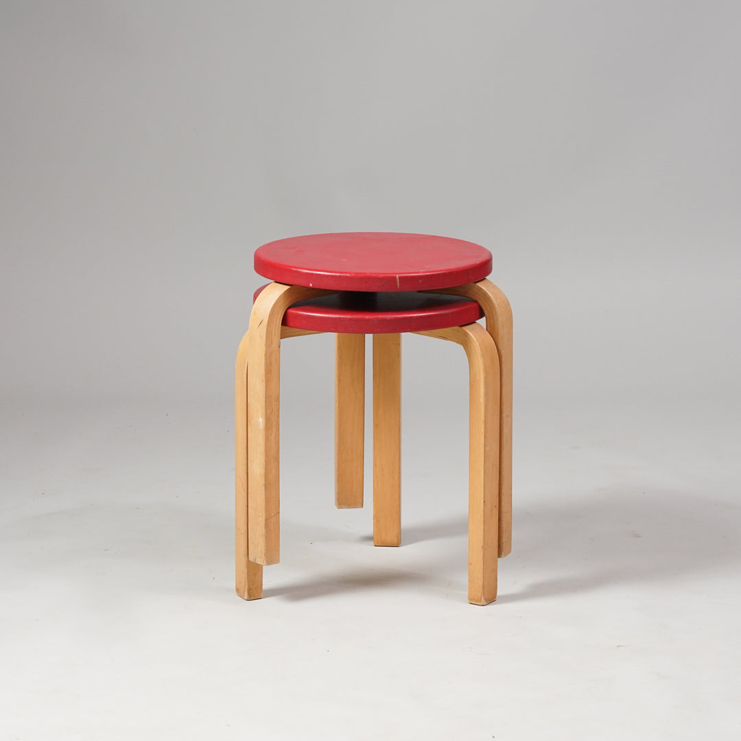 A stool with three legs and red round seat. Made of birch.