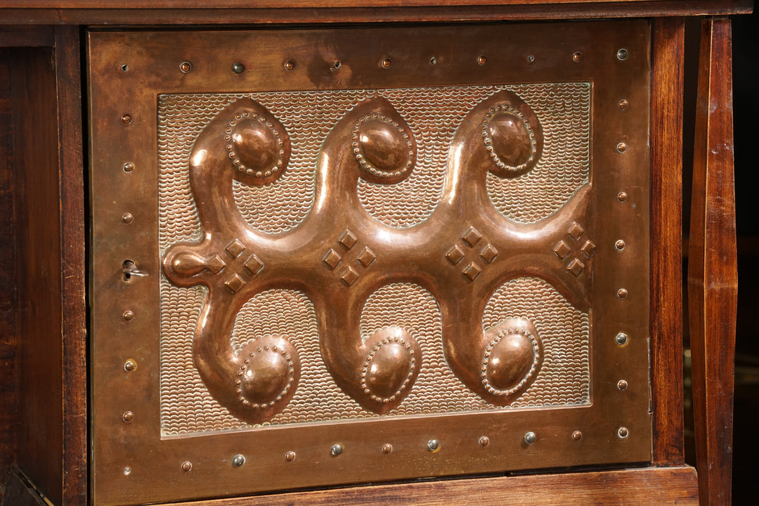 A cabinet made of solid wood with four open shelves and nine cabinets with doors. The doors have keyholes and either copper decorations or wooden engravings. 